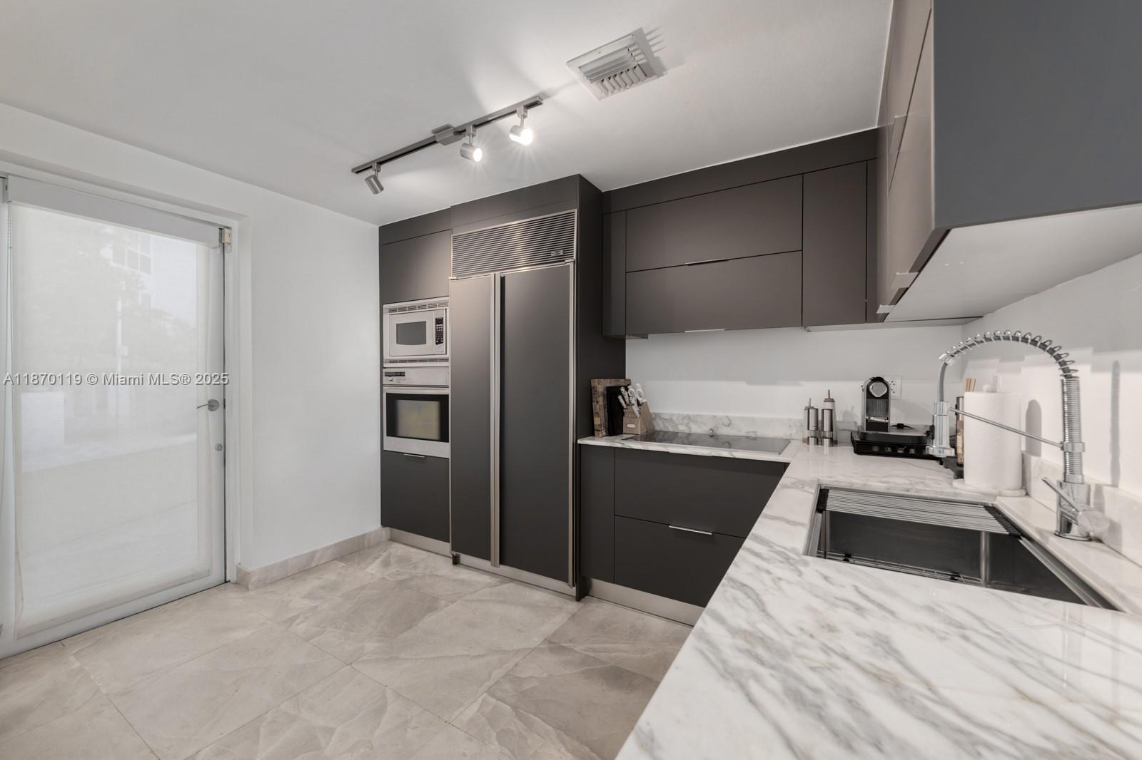 400 Alton Road, Unit TH1A Miami Beach, FL 33139 - Photo 11 of 45 a kitchen with granite countertop a refrigerator and a sink