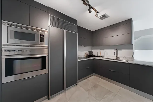 a kitchen with stainless steel appliances kitchen island granite countertop a refrigerator stove and sink