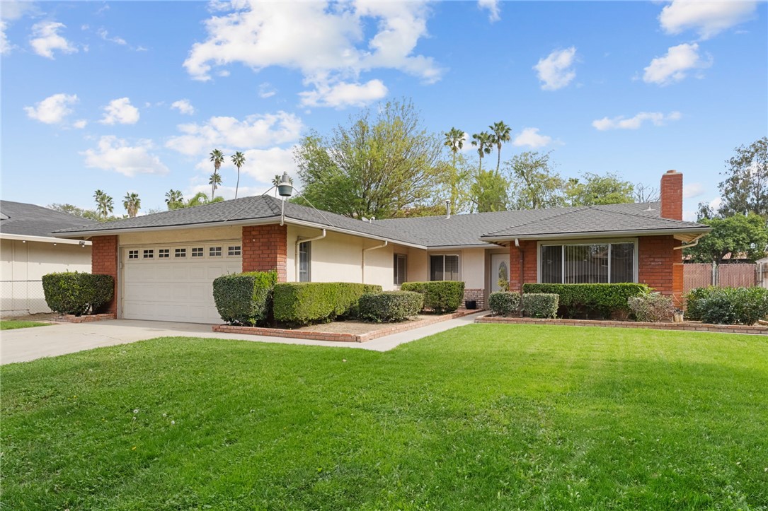 Single-story home with brick accents, a clean driveway, and a wide front lawn with mature landscaping.
