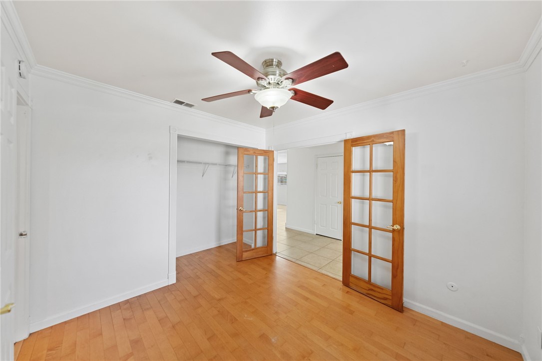 6090 Meadowbrook Lane Riverside, CA 92504 - Photo 19 of 37 Bedroom 1 Light-filled room with wood flooring, crown molding, and a ceiling fan, plus French doors and an open closet area.