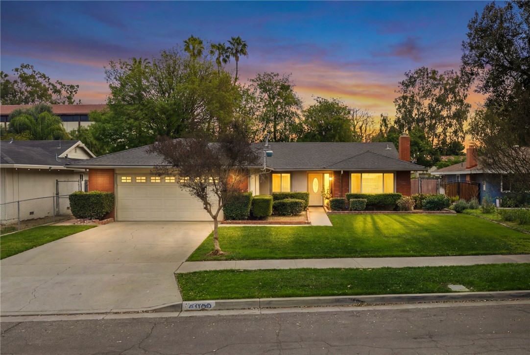 6090 Meadowbrook Lane Riverside, CA 92504 - Photo 2 of 37 Inviting curb appeal at dusk with warm interior lighting and a spacious driveway leading to the attached garage.