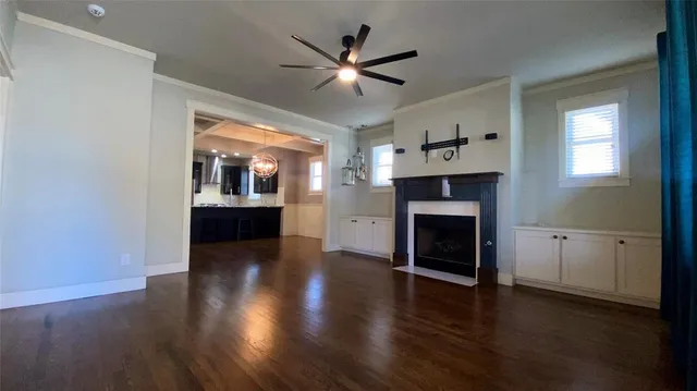 a view of a livingroom with a fireplace a ceiling fan and wooden floor