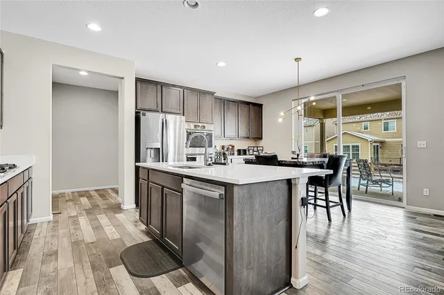 a kitchen with stainless steel appliances granite countertop a stove refrigerator and a dining table with wooden floor