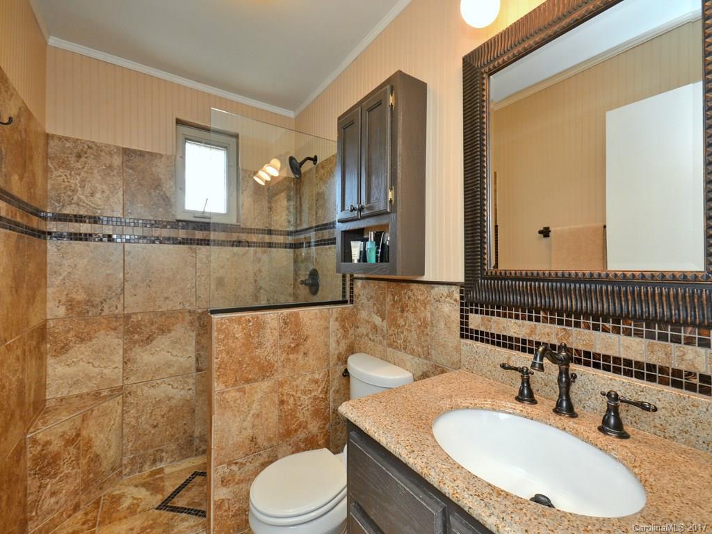 338 The High Road Waynesville, NC 28786 - Photo 11 of 19 a bathroom with a granite countertop sink toilet a mirror and shower