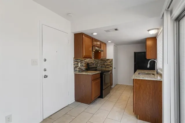 a kitchen with stainless steel appliances granite countertop a stove a sink and a refrigerator