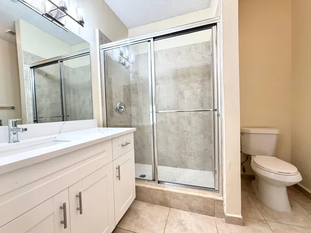 a bathroom with a shower sink vanity mirror and toilet