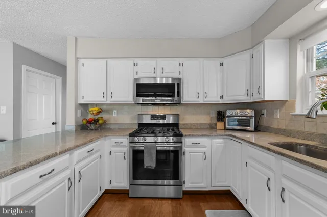 a kitchen with granite countertop a sink and a stove next to a large window