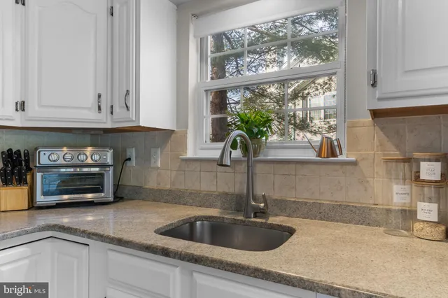 a kitchen with stainless steel appliances kitchen island granite countertop a refrigerator a stove top oven and a sink with wooden floor