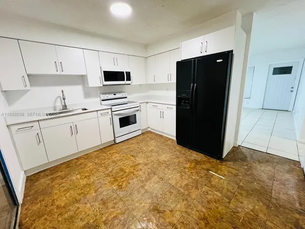 a kitchen with white cabinets and refrigerator