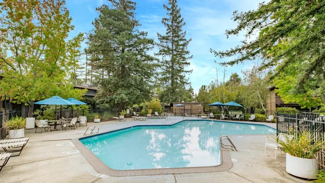 a view of swimming pool with outdoor seating and trees in the background