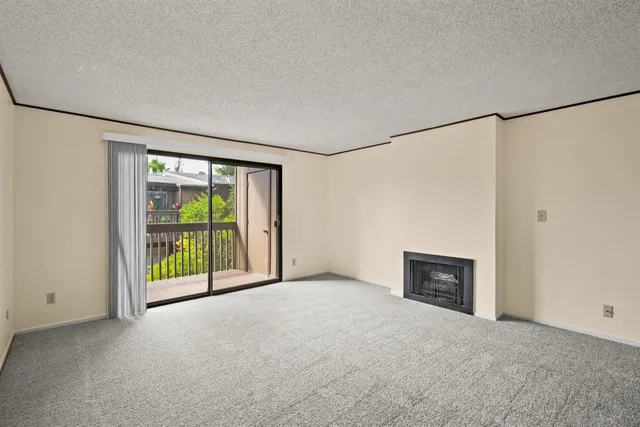 a view of an empty room with a fireplace and a window