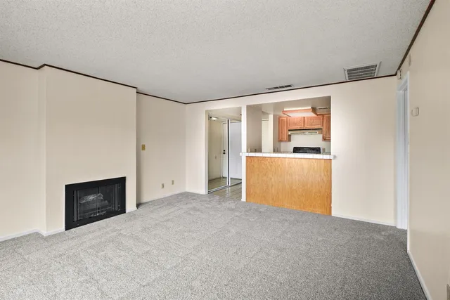 a view of an empty room with a fireplace and a window