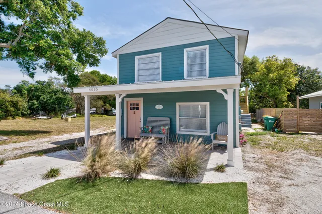 a front view of a house with a yard and potted plants