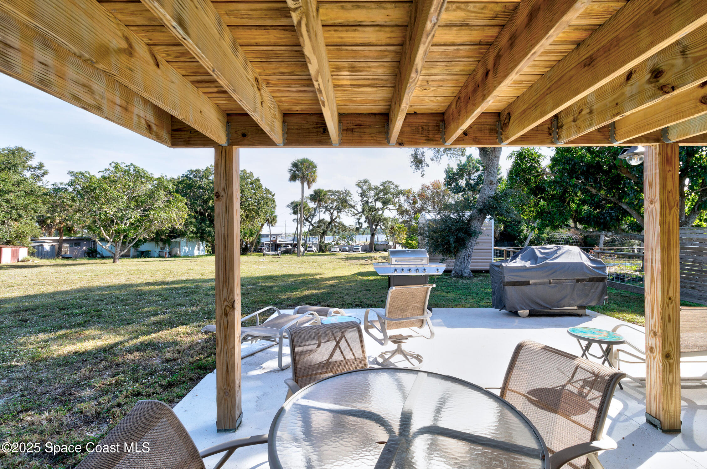 4055 Palm Avenue Micco, FL 32976 - Photo 47 of 58 a view of a patio with table and chairs potted plants with wooden floor and fence