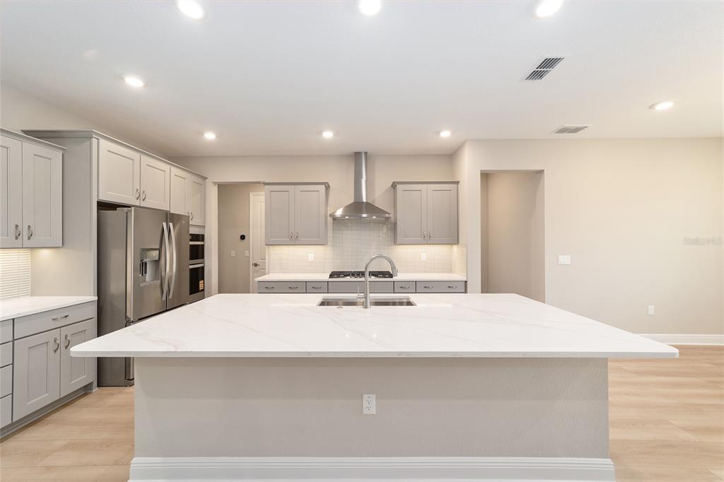 10305 Southwest 105th Street Ocala, FL 34481 - Photo 20 of 44 a large white kitchen with stainless steel appliances kitchen island a stove a refrigerator a oven and white cabinets