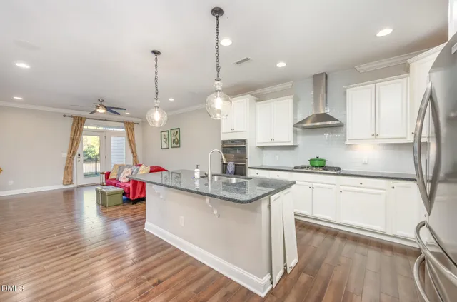 a kitchen with stainless steel appliances granite countertop a sink dishwasher and white cabinets with wooden floor