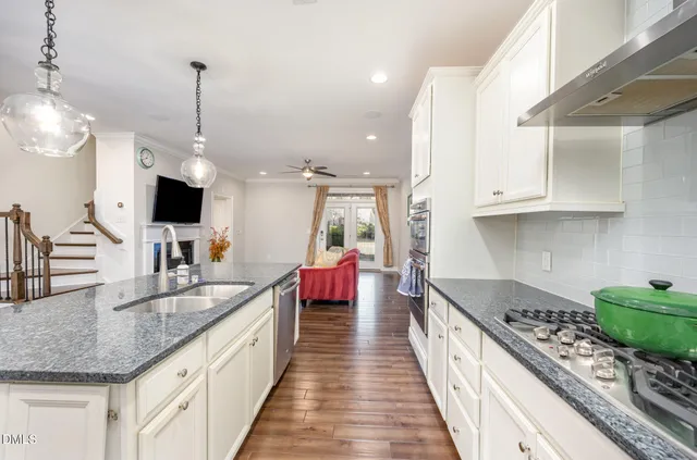 a kitchen with stainless steel appliances granite countertop a sink counter space and a view of living room