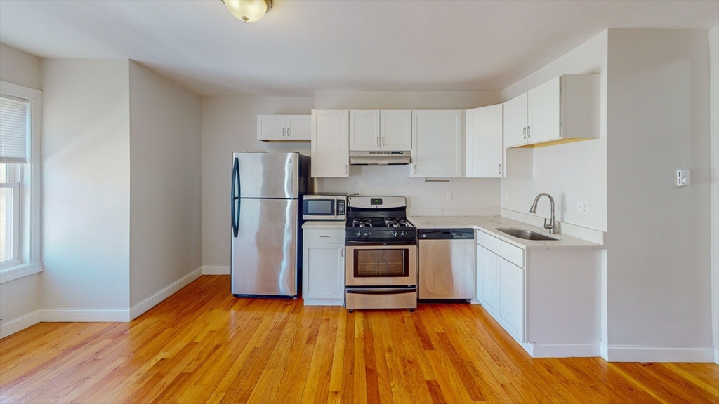 67 Marion Street, Unit 3 Boston, MA 02128 - Photo 2 of 16 a kitchen with a sink a refrigerator and a stove top oven