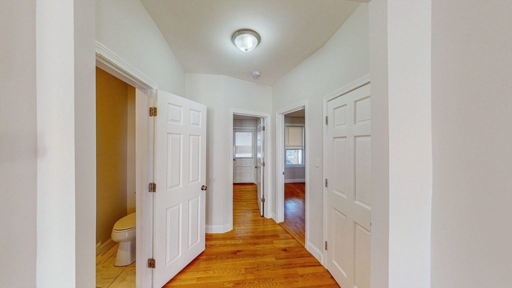 67 Marion Street, Unit 3 Boston, MA 02128 - Photo 7 of 16 a view of a hallway with white walls and a bathroom