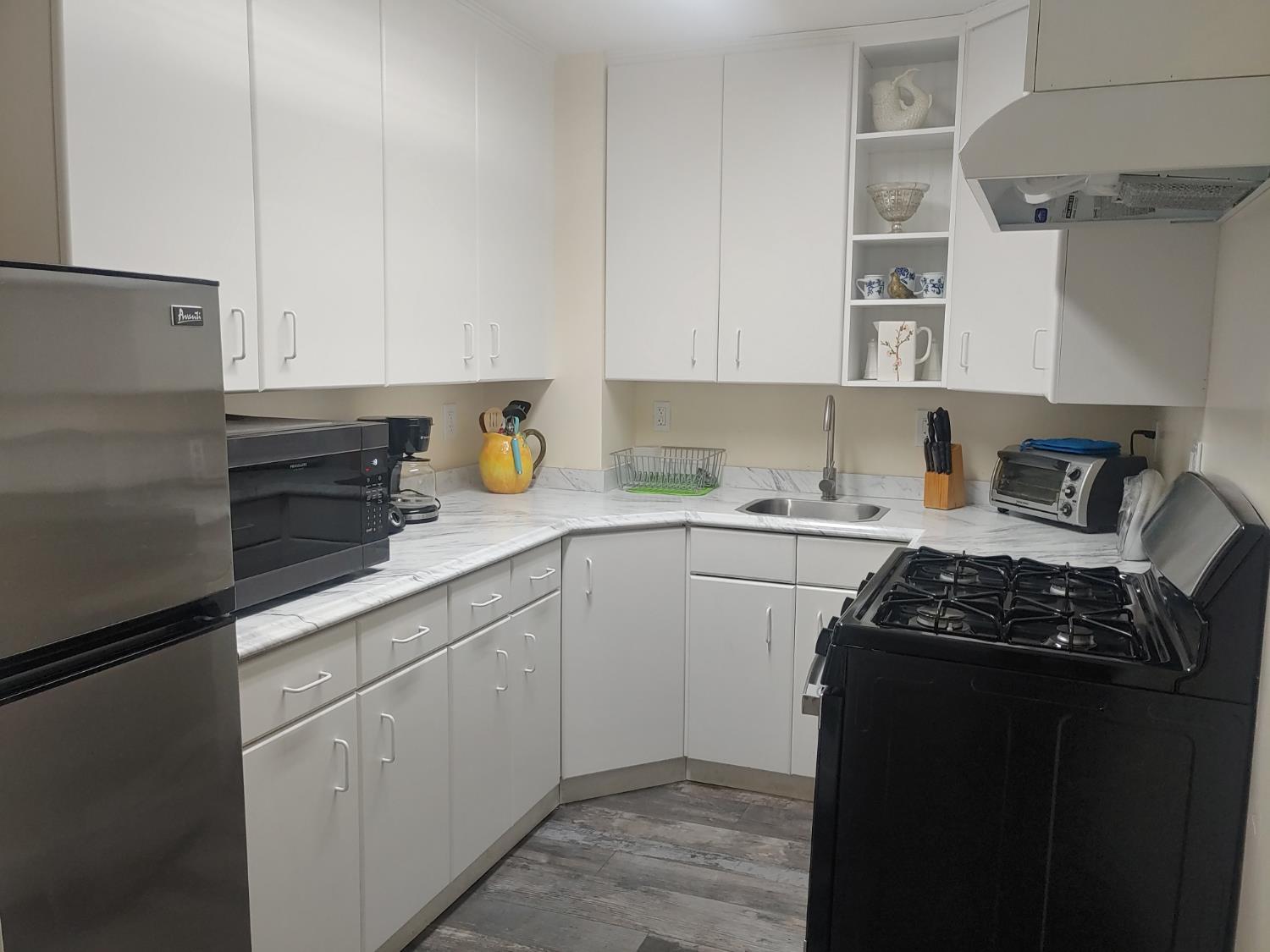 1333 Highway 174 Colfax, CA 95713 - Photo 13 of 88 kitchen with black silver appliances, open shelves, under cabinet range hood, white cabinets, and dark vinyl plank finished floors