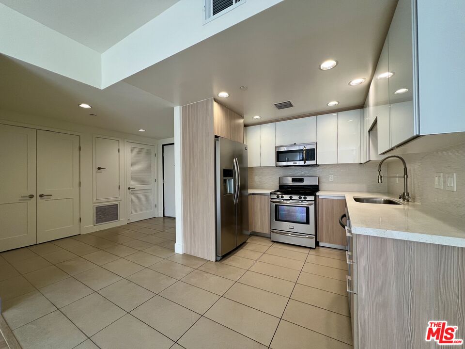 11715 Bellagio Road, Unit 204 Los Angeles, CA 90049 - Photo 4 of 27 a kitchen with stainless steel appliances granite countertop a refrigerator sink and stove