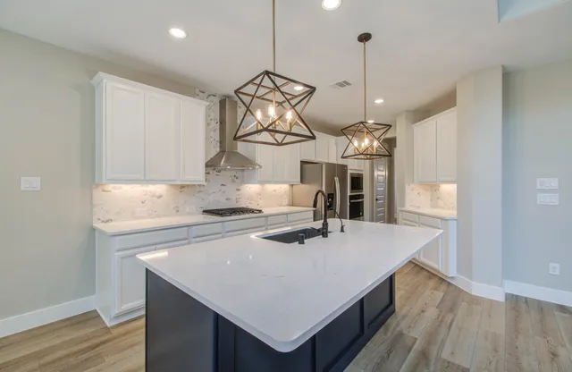 a kitchen with granite countertop a stove a sink dishwasher and white cabinets with wooden floor