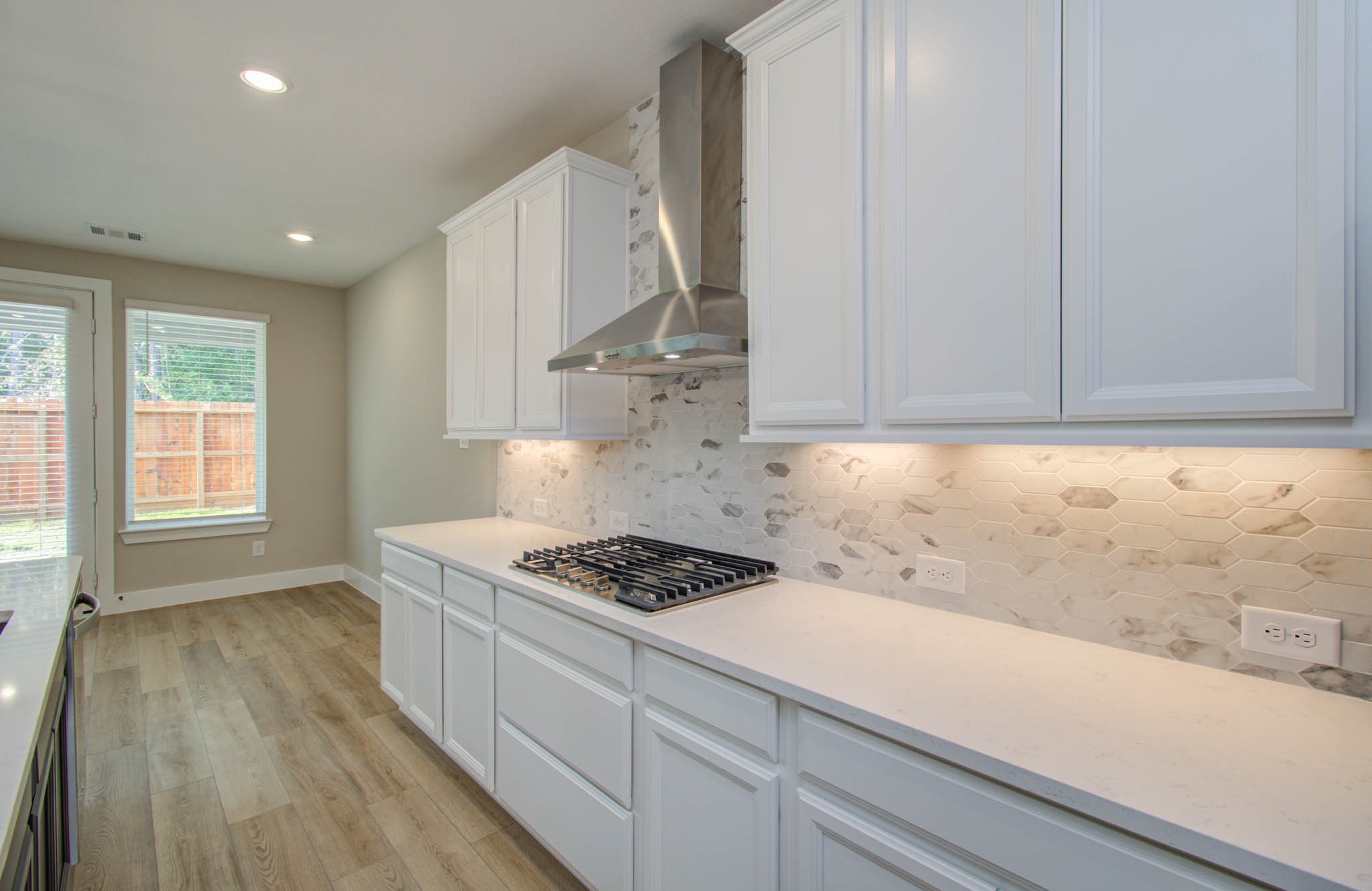 9950 Wild Indigo Circle Conroe, TX 77385 - Photo 16 of 50 a kitchen with granite countertop a stove a sink dishwasher and white cabinets with wooden floor