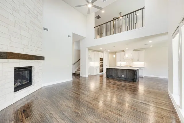 a living room with stainless steel appliances kitchen island a fireplace and wooden floor