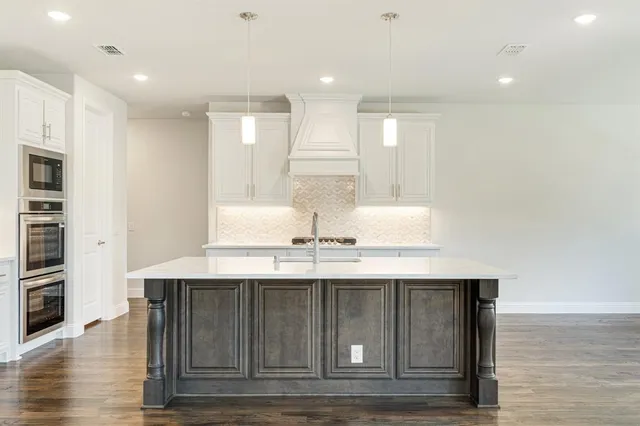 a kitchen with kitchen island granite countertop a sink and cabinets