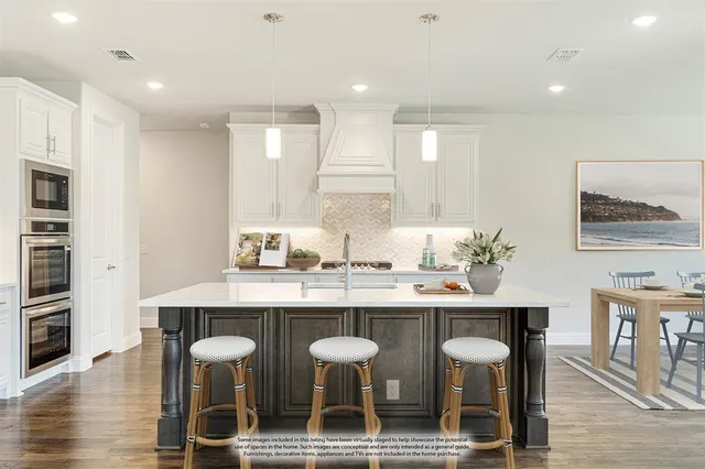 a kitchen with stainless steel appliances granite countertop a dining table chairs and sink
