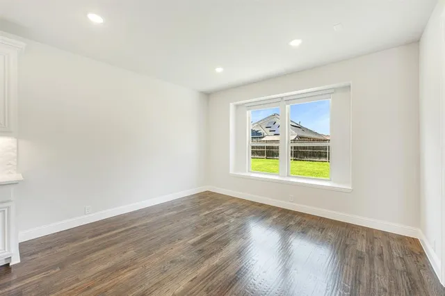 an empty room with a window and wooden floor