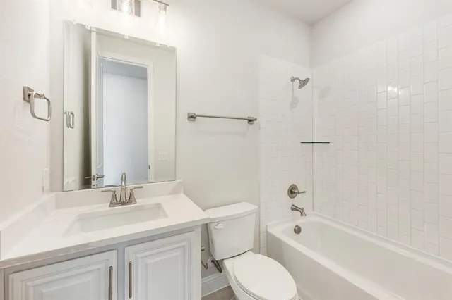 a bathroom with a granite countertop sink a toilet and shower