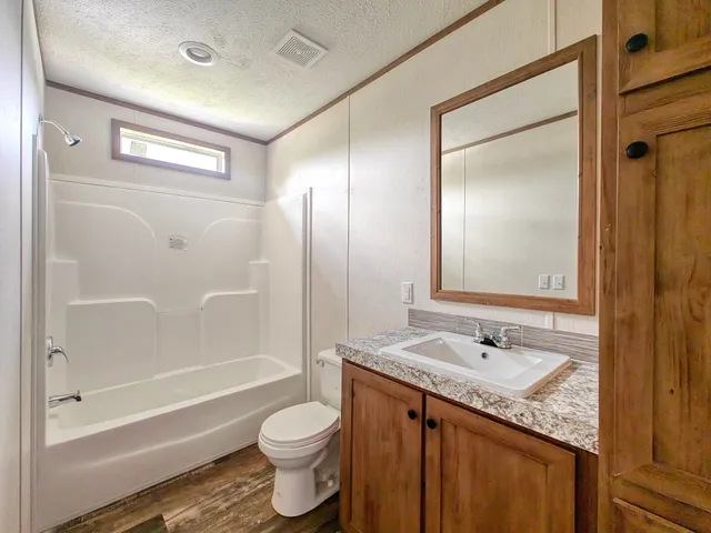 a bathroom with a granite countertop sink toilet and shower