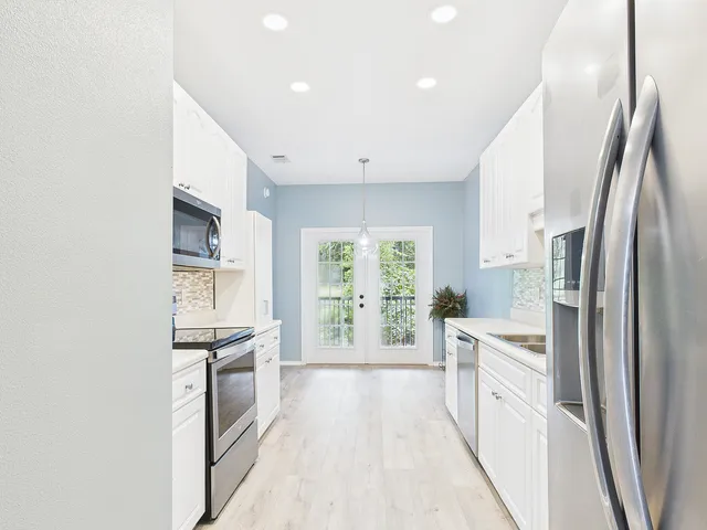 a large kitchen with cabinets stainless steel appliances a sink and a counter top space