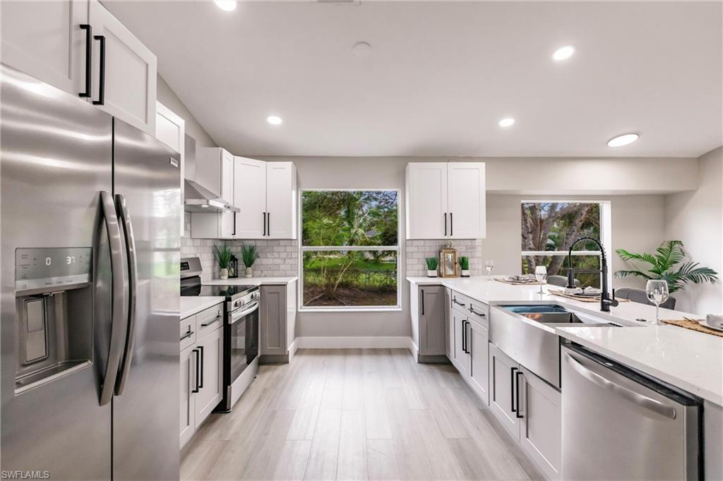 18289 Hepatica Road Fort Myers, FL 33967 - Photo 11 of 45 a kitchen with stainless steel appliances a sink dishwasher a stove a refrigerator and a oven with wooden floor