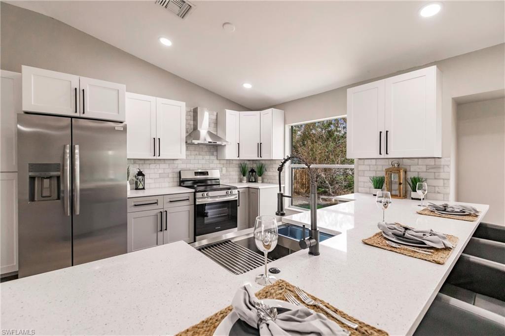 18289 Hepatica Road Fort Myers, FL 33967 - Photo 16 of 45 a kitchen with a refrigerator a stove a sink dishwasher a dining table and chairs with wooden floor