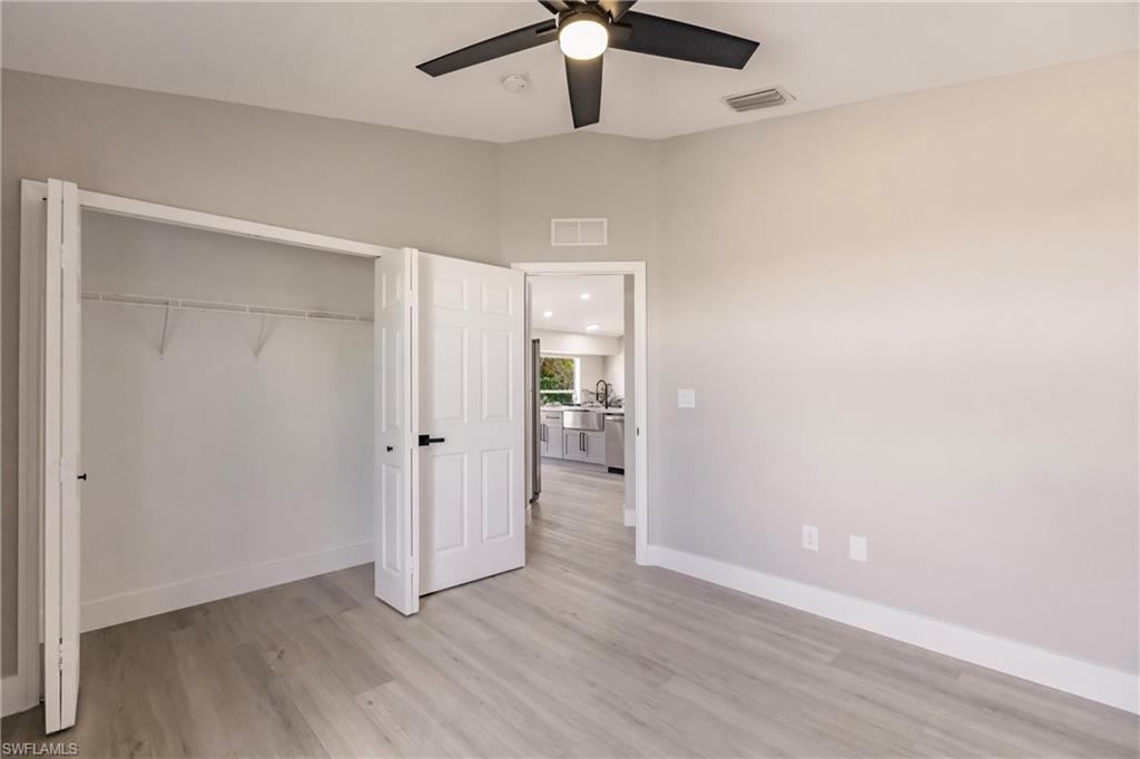 18289 Hepatica Road Fort Myers, FL 33967 - Photo 29 of 45 an empty room with wooden floor a ceiling fan and kitchen view