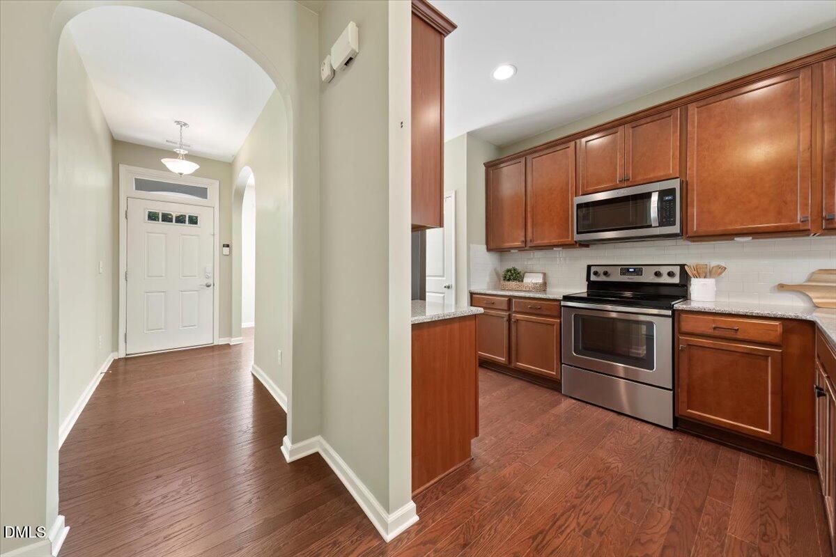 7328 Caversham Way Raleigh, NC 27617 - Photo 10 of 35 a kitchen with granite countertop wooden floors stainless steel appliances and a sink