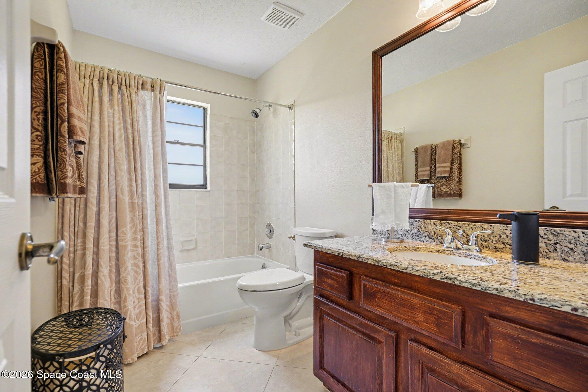 873 Ridge Lake Drive Melbourne, FL 32940 - Photo 20 of 27 a bathroom with a granite countertop sink a toilet a mirror and shower