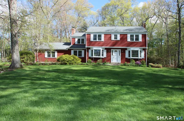 a front view of a house with garden and trees
