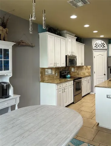 a kitchen with kitchen island granite countertop a sink cabinets and stainless steel appliances