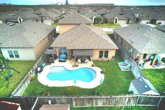 an aerial view of a house with swimming pool and a yard