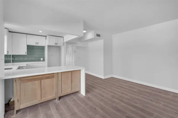 a large kitchen with a sink and wooden floor