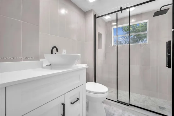 a bathroom with a sink a mirror a toilet and shower