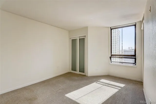 a view of an empty room with cabinet and a window