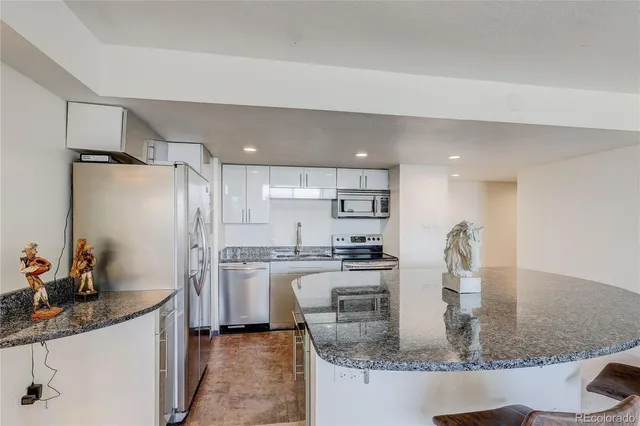 a kitchen with stainless steel appliances granite countertop a sink a stove and a refrigerator