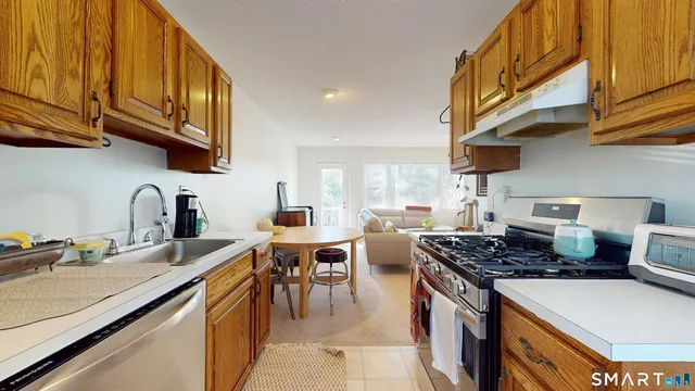 a kitchen with stainless steel appliances granite countertop a sink a stove and a wooden cabinets