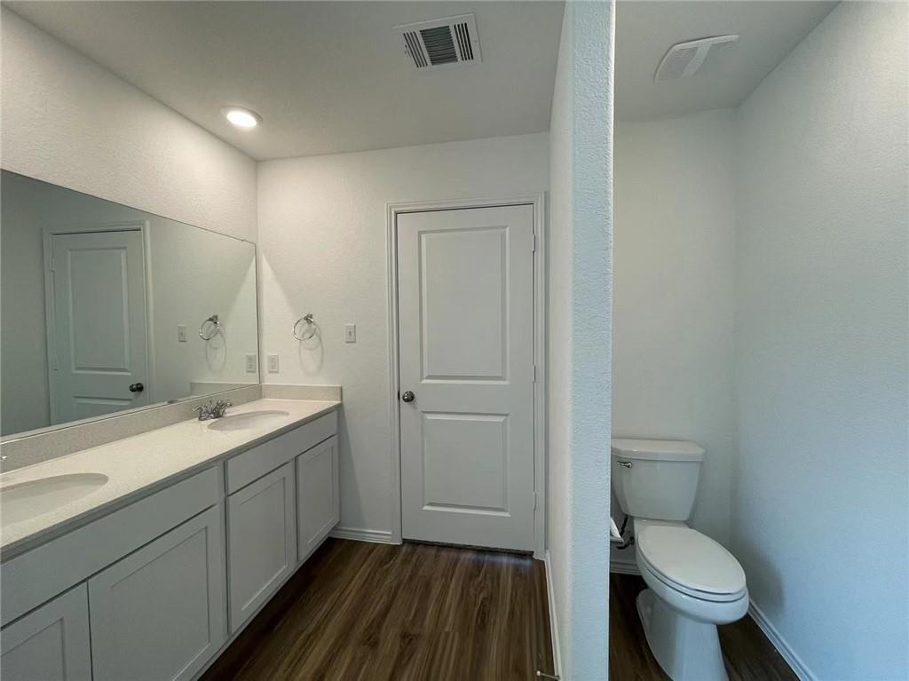 409 Bluejack Way Hutto, TX 78634 - Photo 22 of 28 a bathroom with a granite countertop toilet a sink and a mirror
