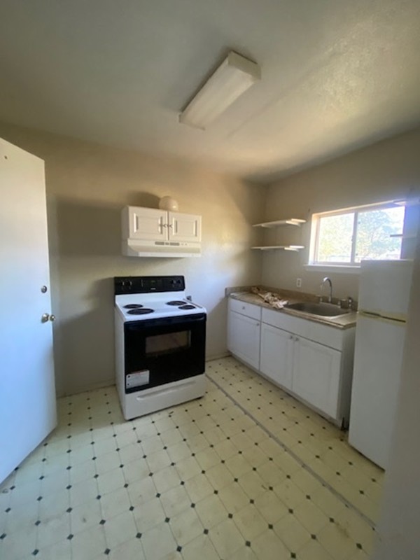 523 South Rio Grande Street Lockhart, TX 78644 - Photo 6 of 16 Kitchen featuring light floors, white cabinetry, white appliances, open shelves, and light countertops