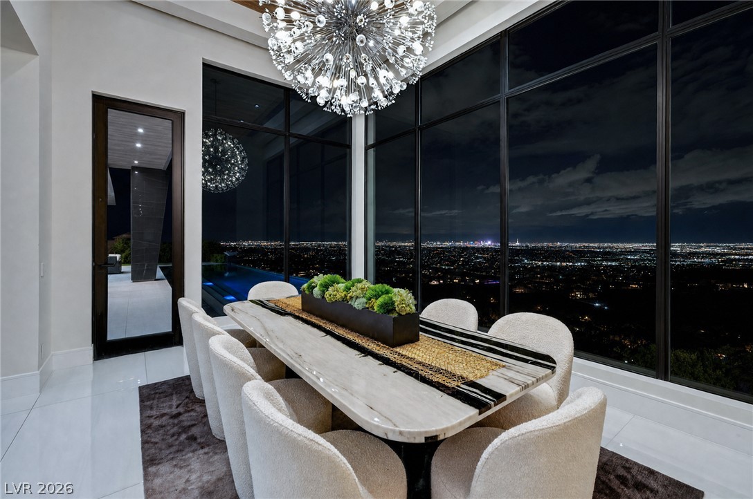 611 Cityview Ridge Drive Henderson, NV 89012 - Photo 32 of 66 Floor-to-ceiling windows frame sweeping night views from this dining room with polished tile flooring.